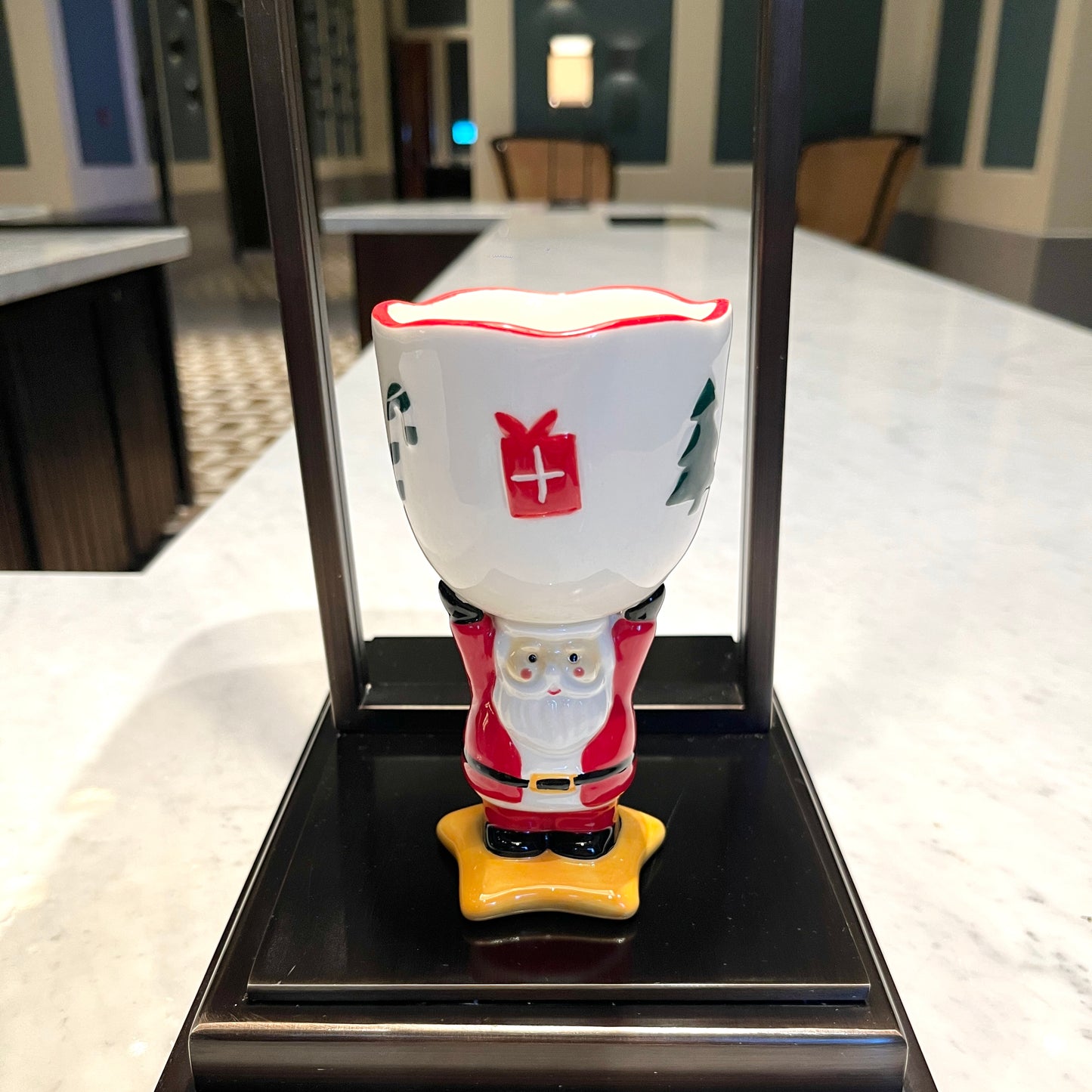 Spiced cranberry cider scented ceramic Santa goblet candle displayed on a countertop in a modern interior setting.