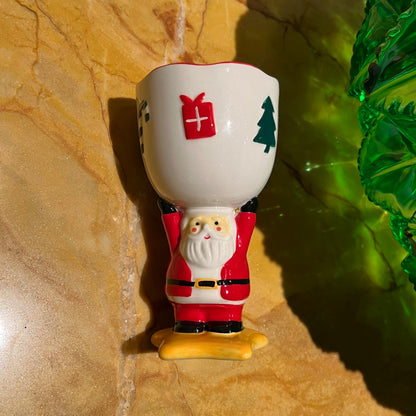 Spiced cranberry cider scented ceramic Santa goblet candle photographed in natural sunlight on a stone surface.